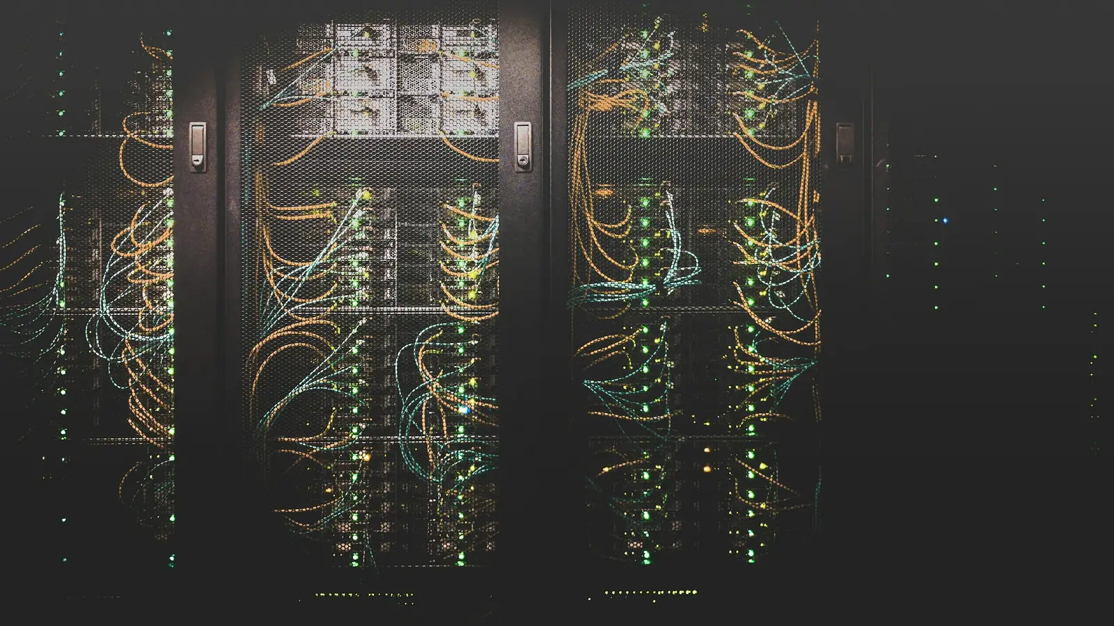 Racks de servidores en la penumbra de un centro de datos, con cables de red y luces de actividad encendidas
